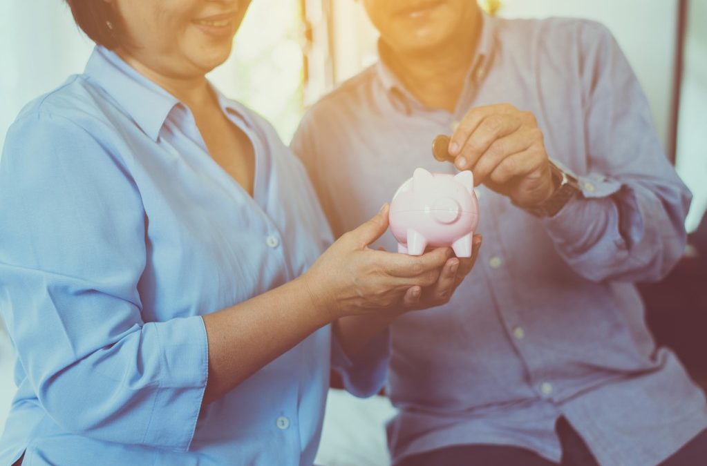 older couple putting money in a piggy bank