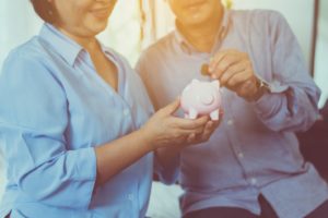 older couple putting money in a piggy bank