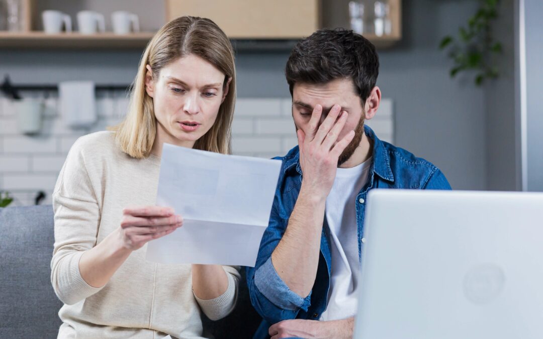 young dark haired man and blonde woman sitting together reading a letter from the IRS