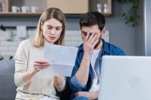 young dark haired man and blonde woman sitting together reading a letter from the IRS